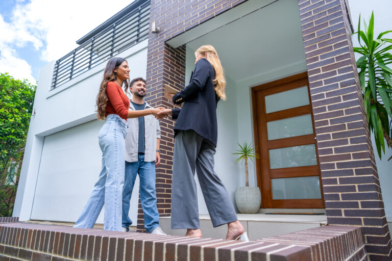 Makelaar ontvangt kijkers bij de voordeur tijdens een open huizen dag in 2026