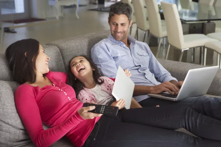 Gezin in nieuwe woning na verhuizing met laptop op de bank
