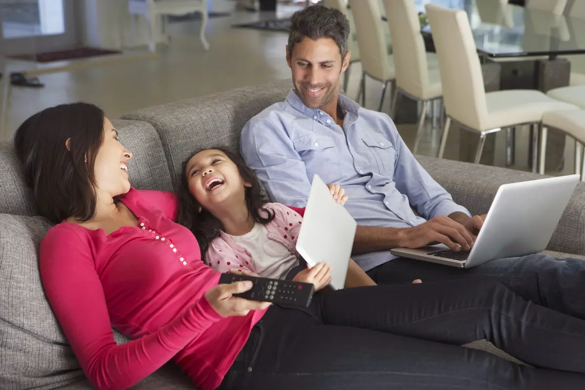 Gezin in nieuwe woning na verhuizing met laptop op de bank