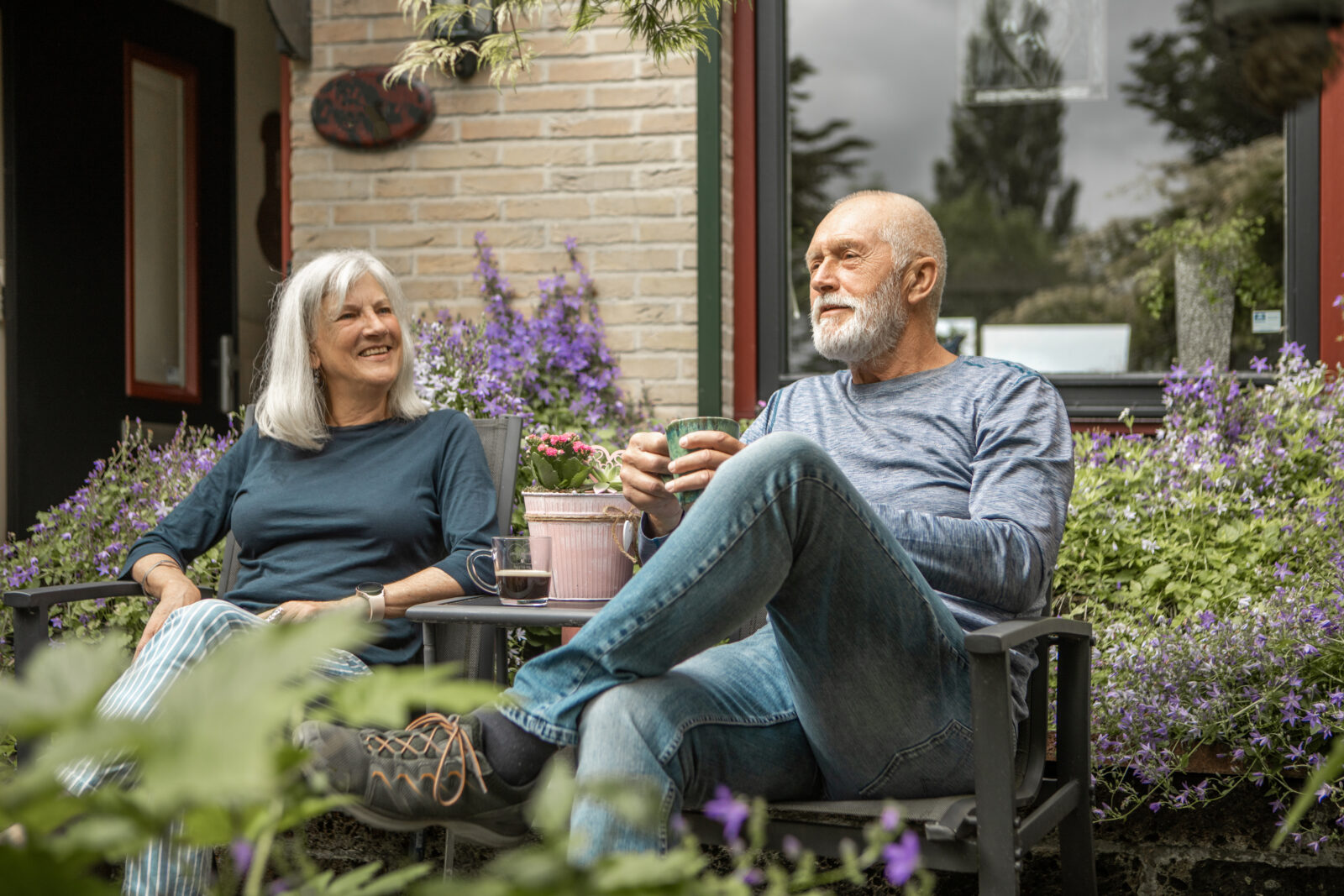 Echtpaar geniet van een onderhoudsarme tuin met tuinmeubelen en bloeiende planten