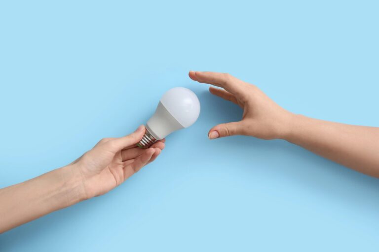 Twee handen geven een ledlamp door tegen een lichtblauwe achtergro