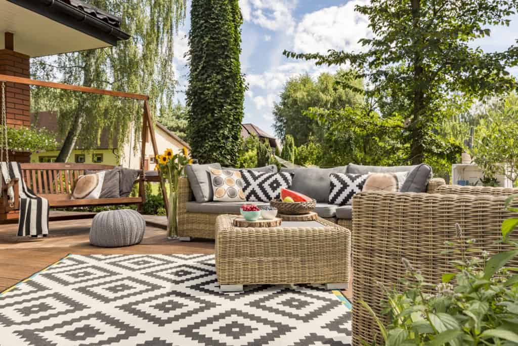 Tuin met rotan loungeset en buitenkleed in natuurlijke kleuren