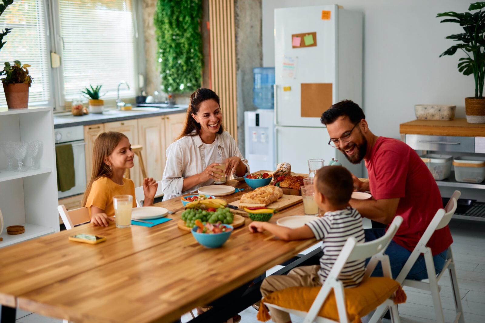 Gezin aan houten eettafel in lichte woonkeuken