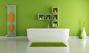 een groene badkamer, met een wit los bad en een design badkamerradiator