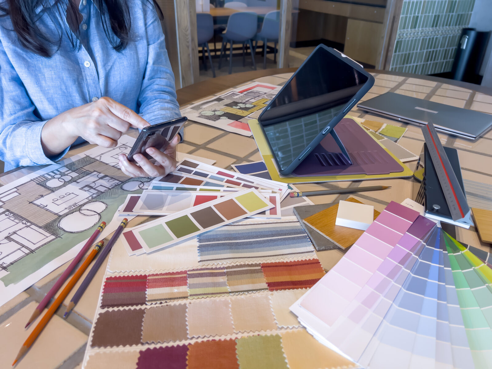 Kleurstalen, stofsamples en interieurontwerptekeningen op tafel bij het kiezen van een kleurenpalet voor een woning