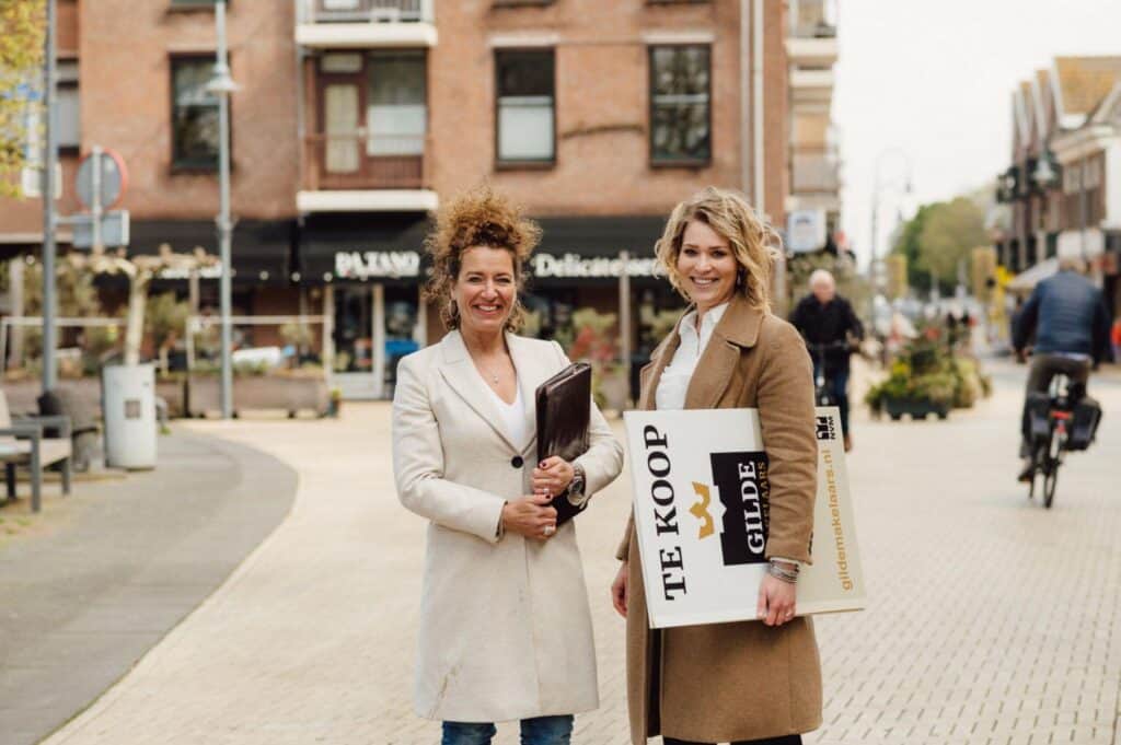 Makelaar met te koop bord in krappe woningmarkt tijdens verkoop van woning