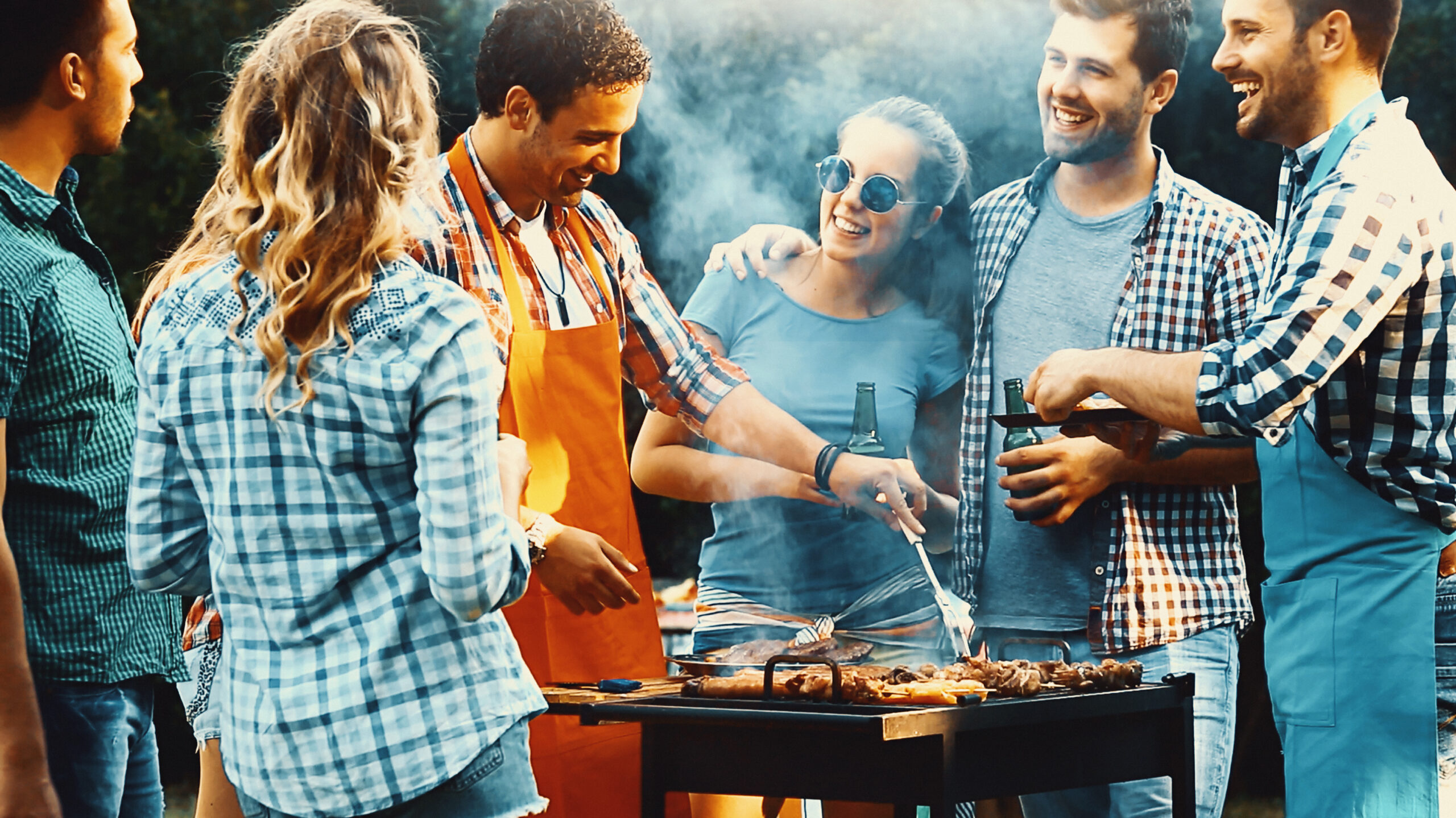 Vriendengroep bij barbecue naast tuinhuis dat kan dienen als mancave of buitenverblijf