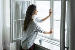 vrouw opent raam en kijkt naar buiten