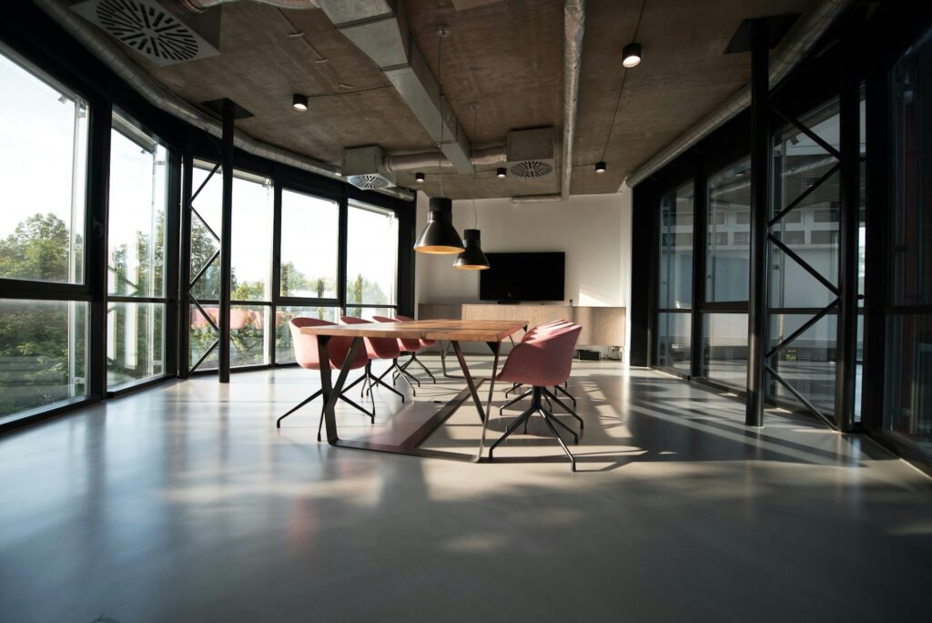 Een vergaderruimte in een modern gebouw met grote ramen en zichtbare ventilatiesystemen aan het plafond, waardoor frisse lucht door het pand stroomt