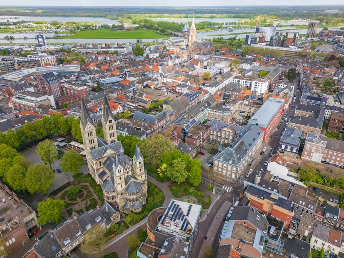 Luchtfoto van het centrum van Roermond, een stad gelegen in Midden-Limburg, met prominente gebouwen zoals de Sint-Christoffelkathedraal en de Munsterkerk, omringd door groene gebieden en wateren.