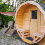 Houten buiten sauna met ligstoelen in een groene tuinomgeving