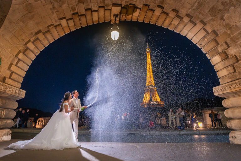 Bruidspaar viert hun verloving bij de Eiffeltoren met een spectaculaire champagne-opening, vastgelegd in een sfeervolle avondfoto