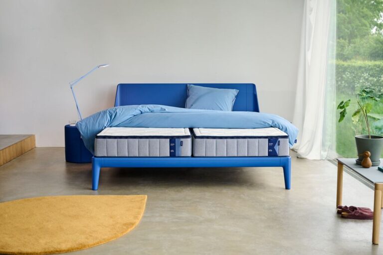 Modern blauw bed met een dubbel matras in een lichte en minimalistische slaapkamer, ideaal voor een frisse start na dieptereiniging van het matras.