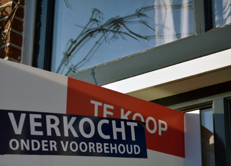 Een 'Te Koop'-bord met de tekst 'Verkocht onder voorbehoud' geplaatst voor een woning.