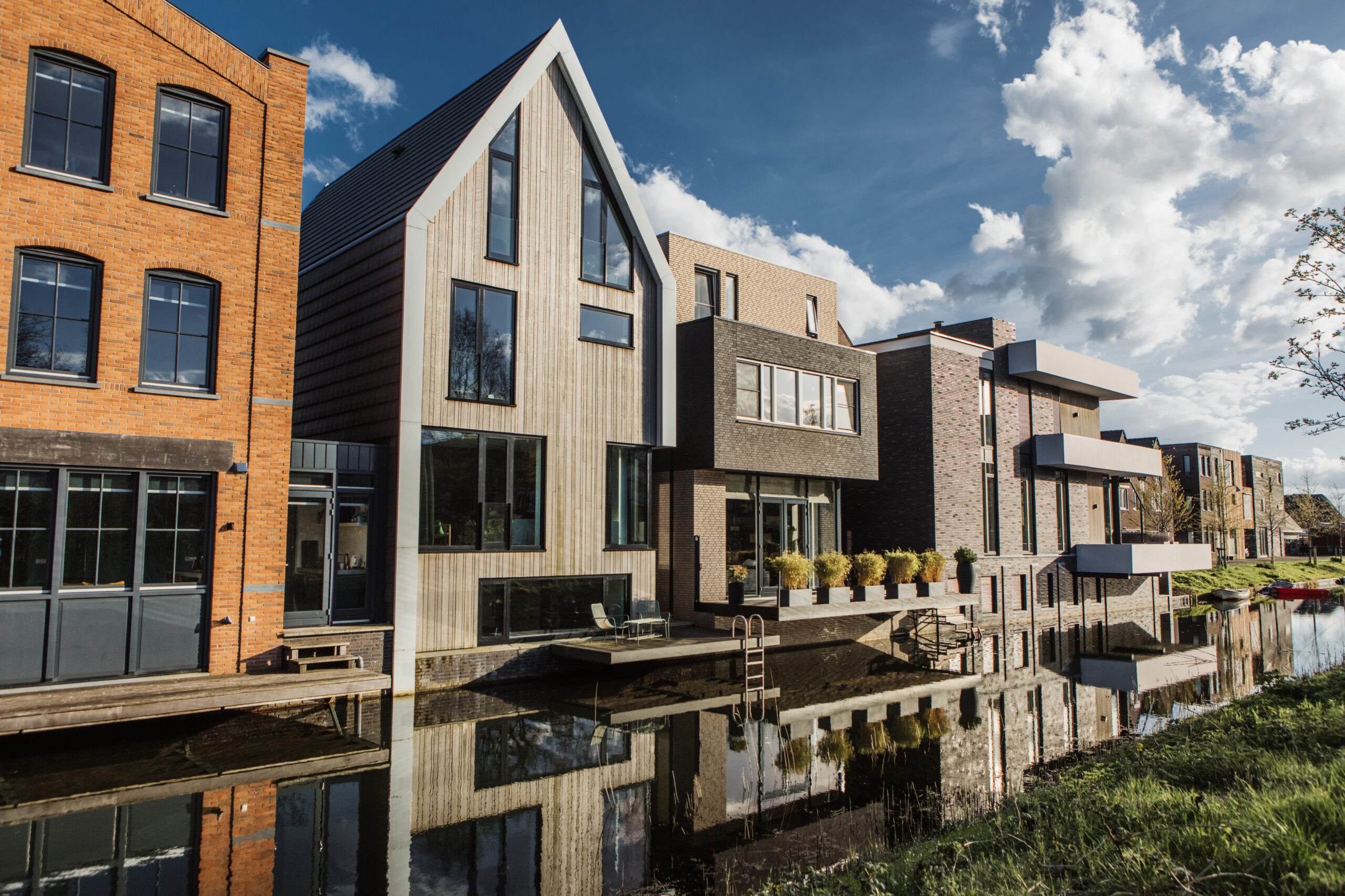 Moderne duurzame woningen langs het water, met diverse architectonische stijlen.