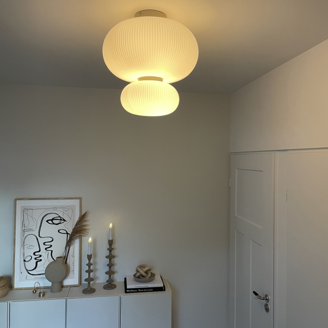 Stijlvolle ruimte met dubbele ribbelglazen plafondlamp en minimalistische decoratie – sfeervolle verlichting in een modern interieur