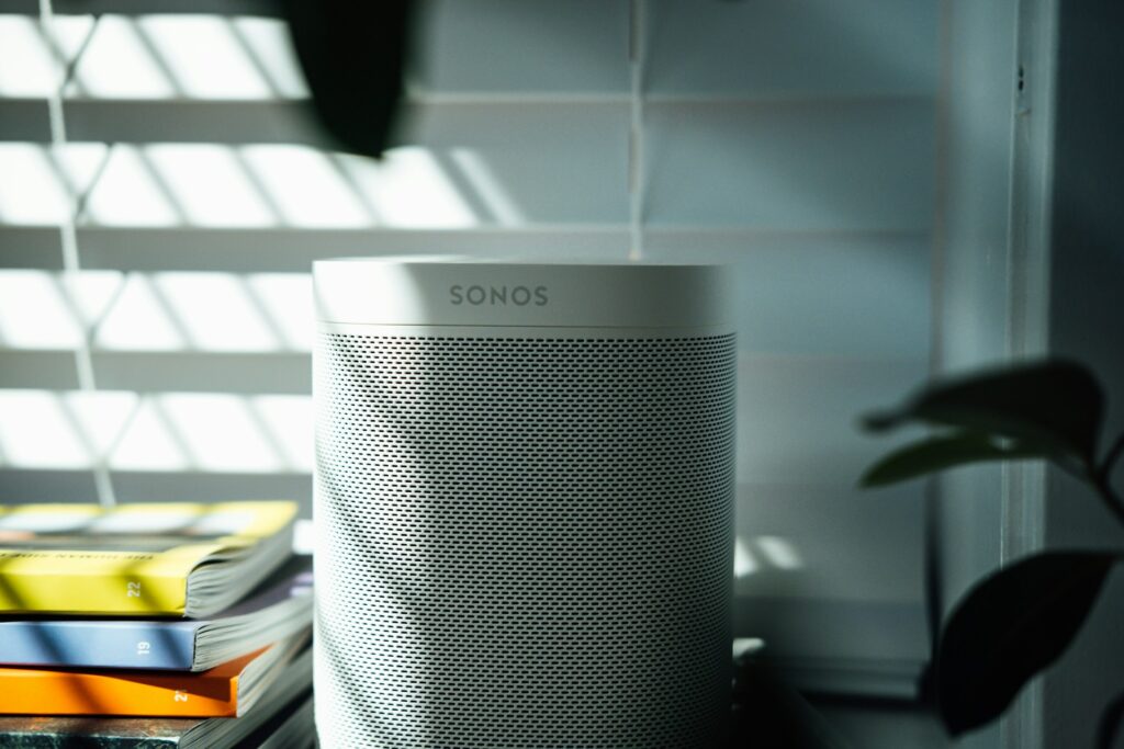 Witte draadloze Sonos-speaker op een tafel met boeken en planten, perfect geïntegreerd in een modern interieur dankzij minimalistisch design