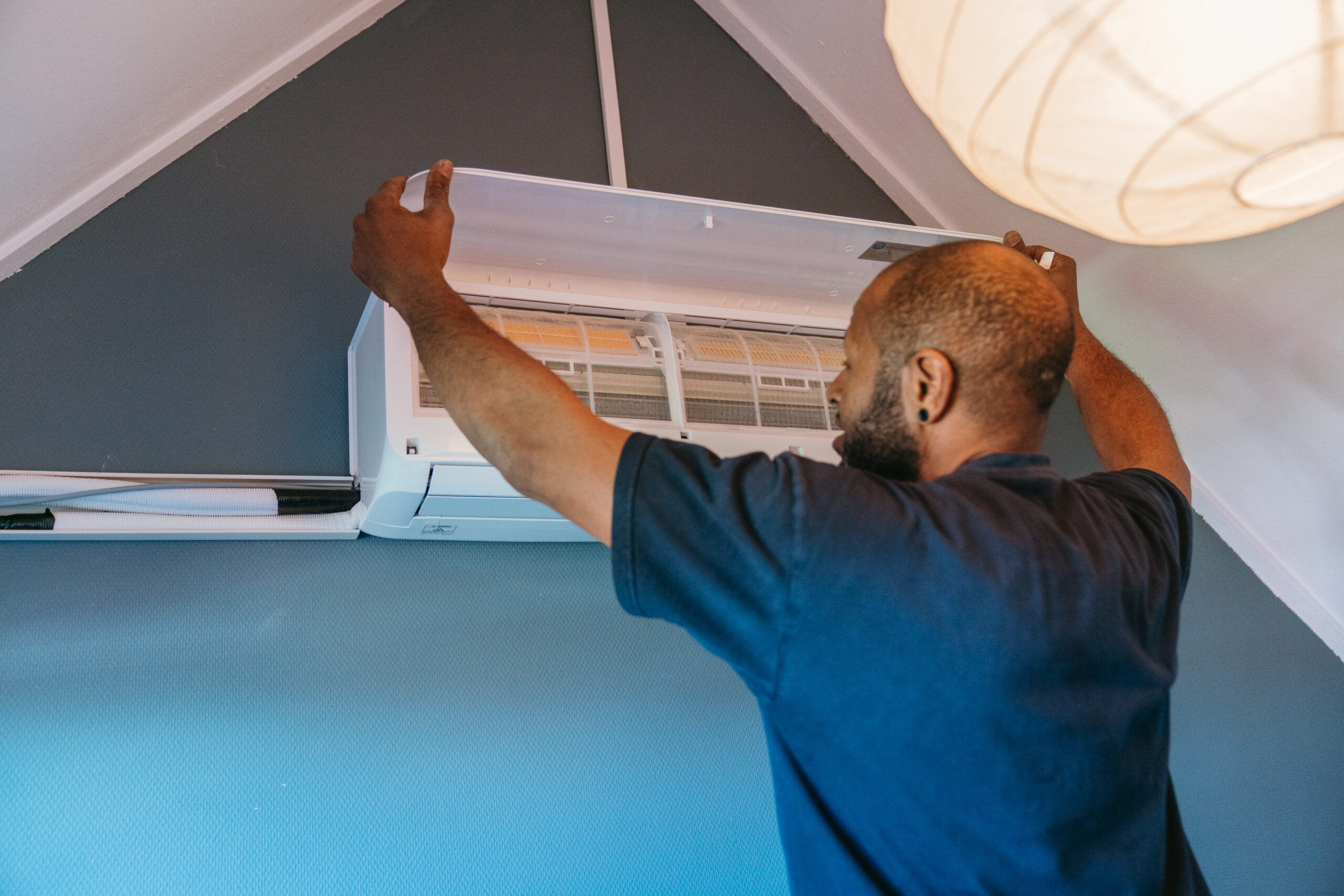 Technicus installeert een vaste airco-unit in een woning onder een schuin plafond.