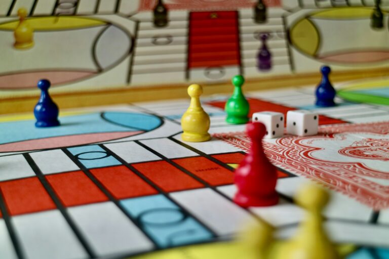 Close-up van een kleurrijk bordspel met pionnen en dobbelstenen, geschikt voor een gezellige spelletjesavond