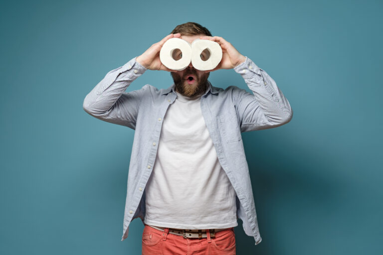 Man met WC-rollen voor zijn ogen, een speelse kijk op het ontwerpen van een stijlvol toilet.