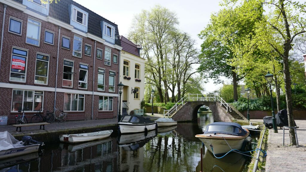 Woningen te koop langs een gracht in Alkmaar met boten en een brug, een kenmerkend beeld van de woningmarkt in 2025.