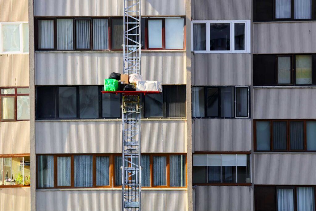 Een verhuislift brengt meubels, dozen en tassen naar een hoger gelegen verdieping van een appartementencomplex. Ideaal voor een snelle en veilige verhuizing zonder zwaar tilwerk.