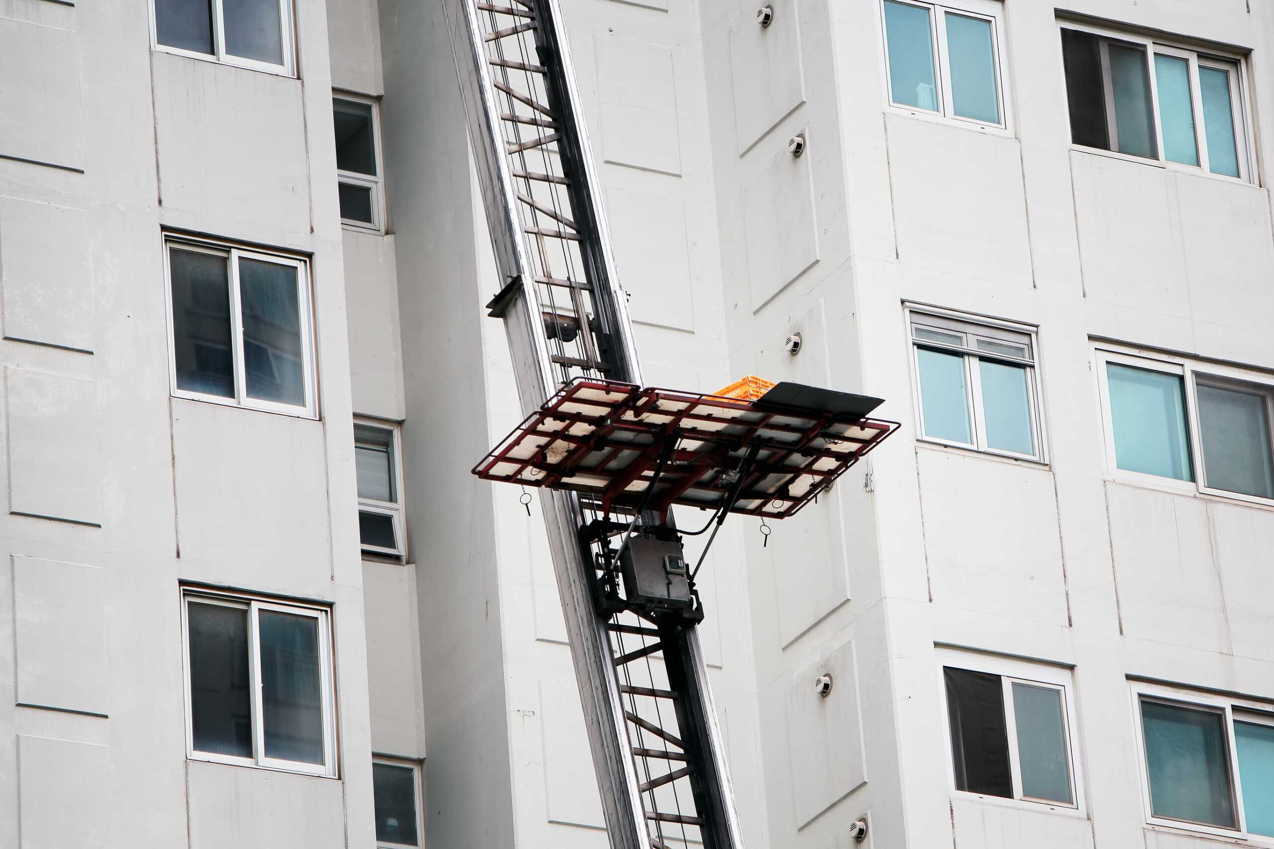 Een verhuislift brengt meubels en dozen via een platform omhoog naar een hoger gelegen verdieping van een appartementengebouw. Ideaal voor verhuizen in drukke steden met smalle straten en hoge gebouwen.