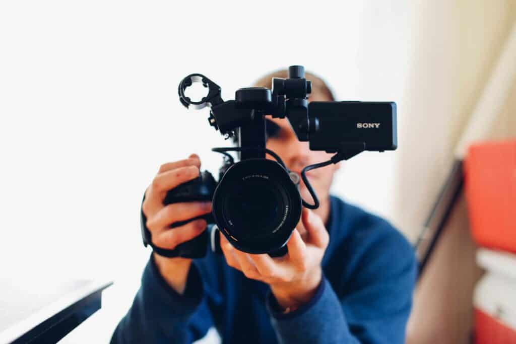 Filmmaker richt een professionele camera op de kijker, klaar voor het opnemen van een vastgoedvideo rondleiding.