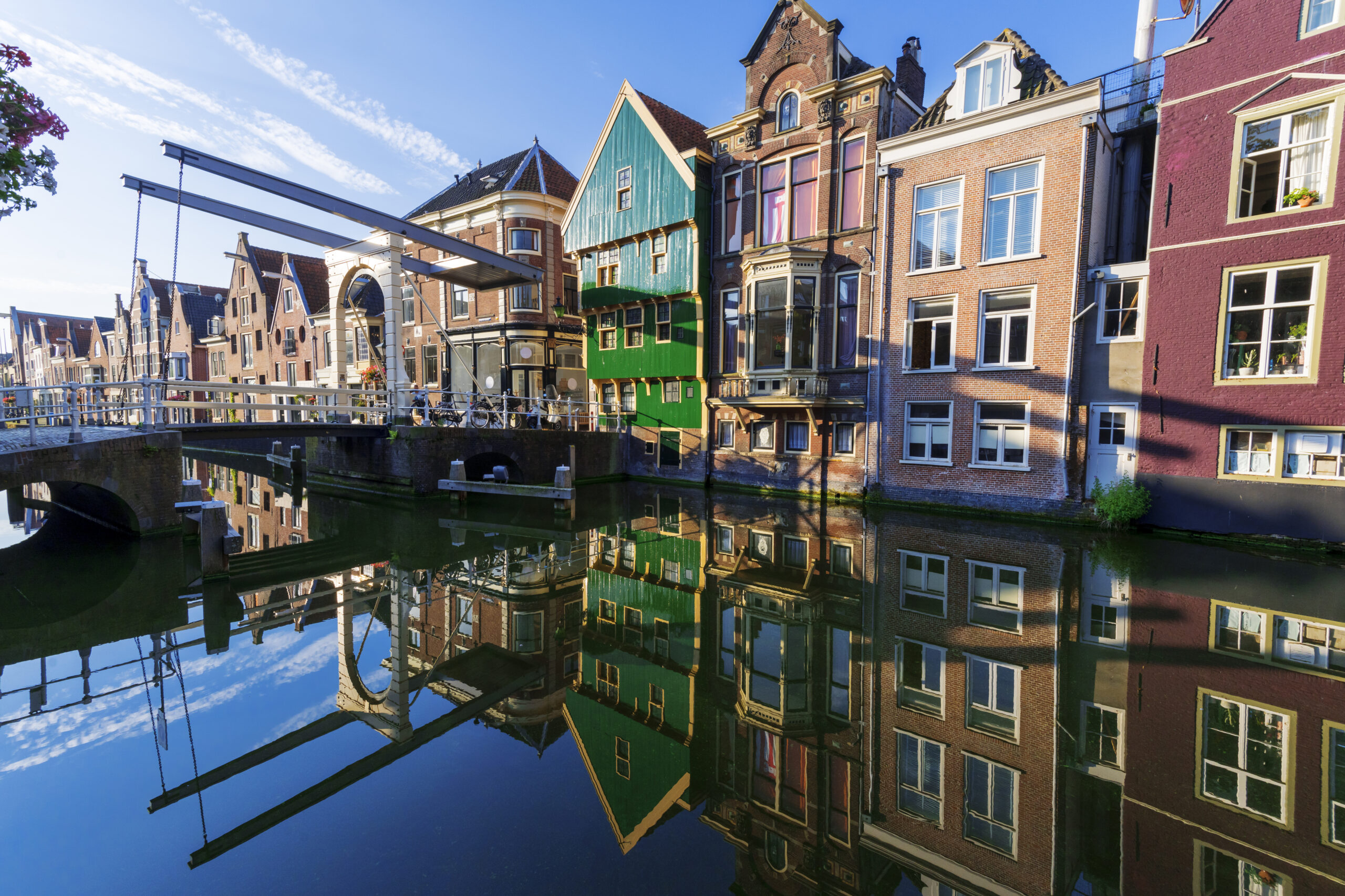 Historische grachtenpanden en brug in Alkmaar weerspiegeld in het water bij zonsopgang.