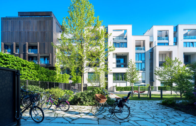 Modern appartementencomplex met groene buitenruimte en fietsen in een stedelijke omgeving.