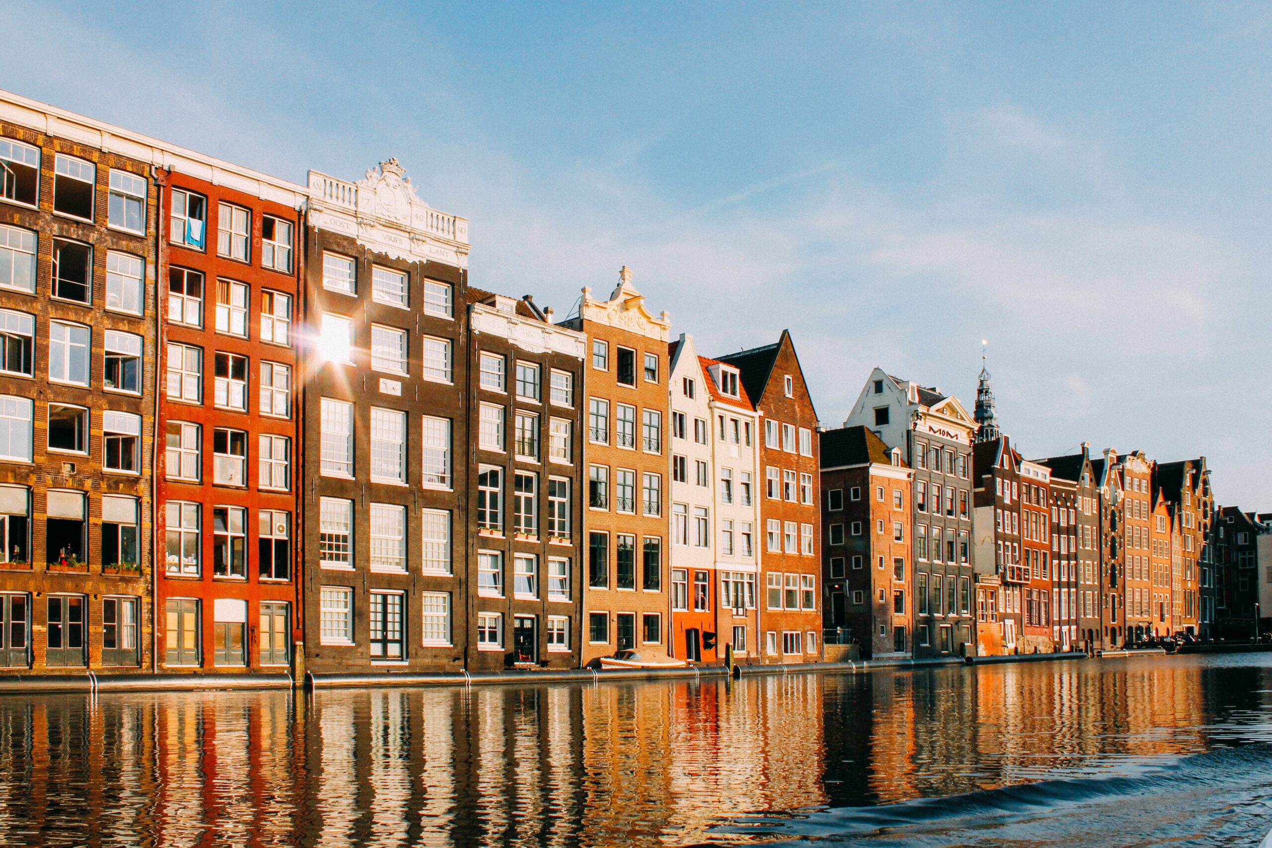 Grachtswoningen in Amsterdam met reflectie in het water, typisch voor de stad."