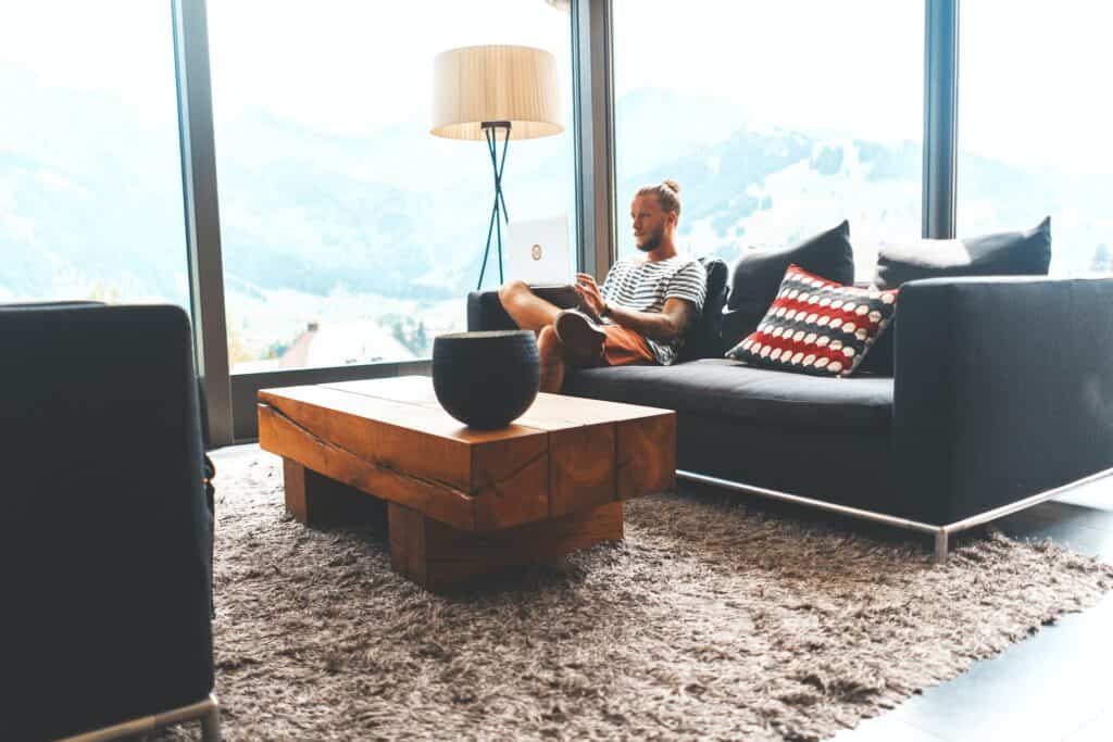 Zithoek met grijs vloerkleed, houten salontafel en moderne bank met uitzicht op berglandschap