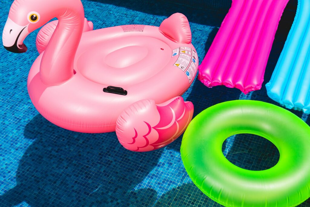 Opblaasbare flamingo, zwemband en luchtbedden drijven in een zwembad – perfecte accessoires voor ontspanning en plezier.