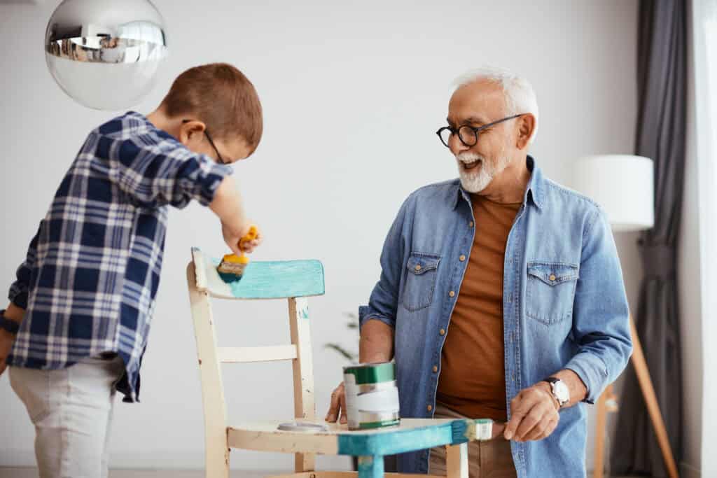 Grootvader en kind verven samen een stoel voor de babykamer – warm, persoonlijk moment