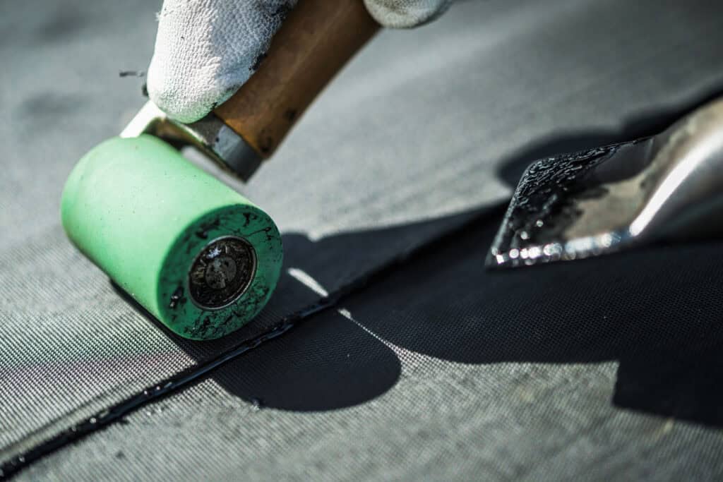 Close-up van het aanbrengen van EPDM dakbedekking met een roller en lijm