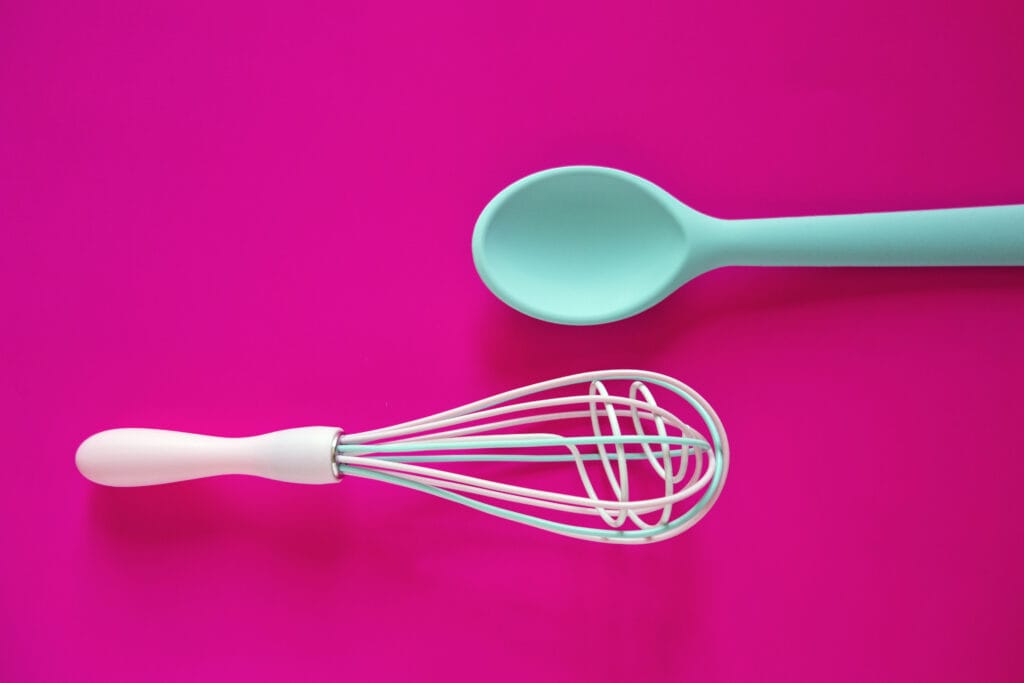 Turquoise garde en lepel op felroze achtergrond, symbolisch voor moderne en kleurrijke keukenaccessoires