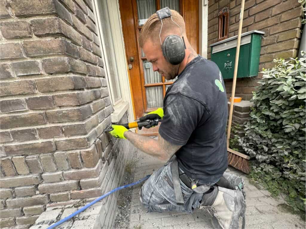Vakman brengt spouwmuurisolatie aan bij een woning voor betere energie-efficiëntie