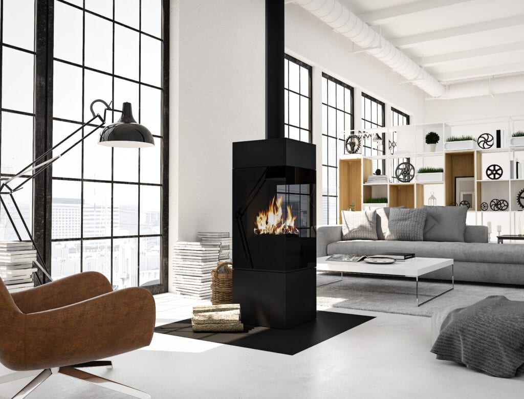 Vrijstaande zwarte houtkachel in een modern industrieel ingerichte woonkamer met leren fauteuil en grijze bank