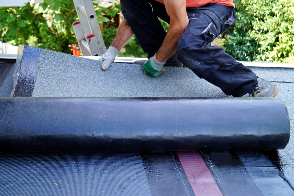 Dakdekker rolt EPDM-dakbedekking uit op een plat dak