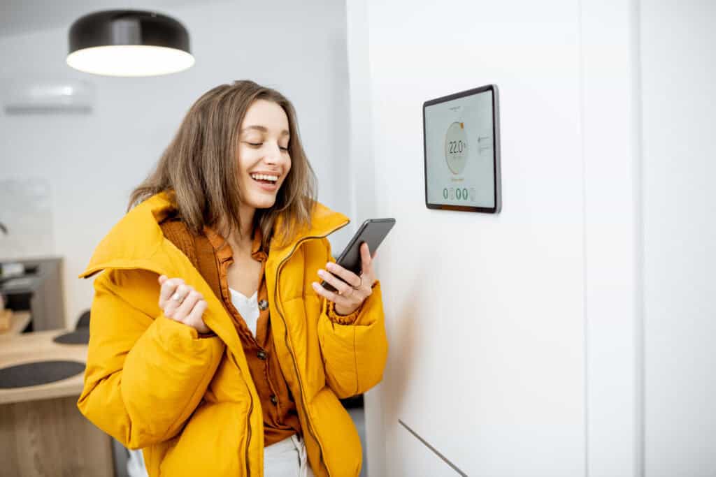 Vrouw gebruikt een app om slimme verwarming te regelen en energie te besparen in huis
