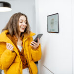 Vrouw gebruikt een app om slimme verwarming te regelen en energie te besparen in huis