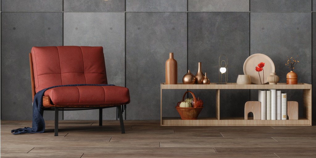 Moderne fauteuil in roestkleurige stof naast een houten dressoir en betonnen wand