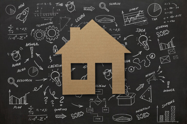 Karton huis voor schoolbord met schema’s over woningkeuze, kopen of huren in 2025