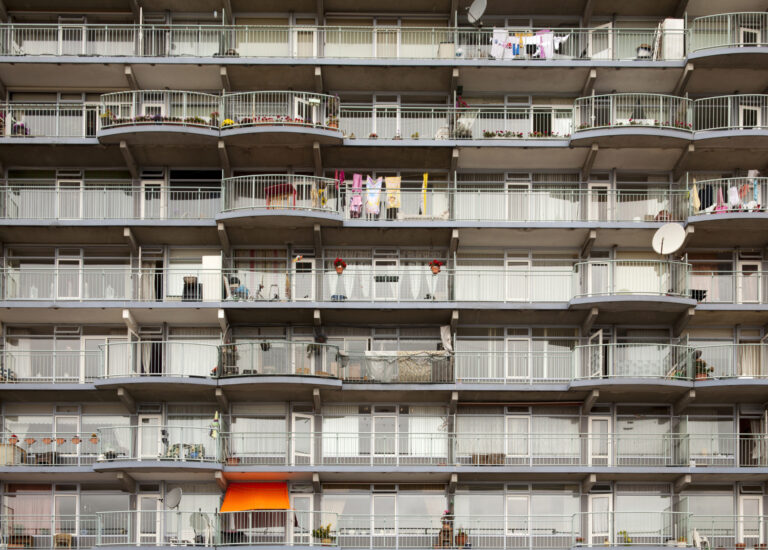Sociale huurflat met kleurrijke balkons, planten en wasgoed in een woonwijk