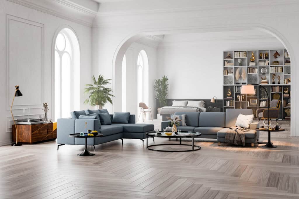 Luxe woonkamer met visgraat houten vloer, blauwe bank en hoge ram