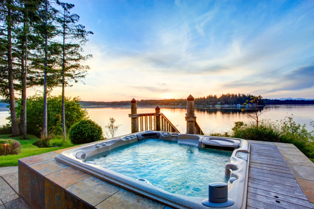 Bubbelende jacuzzi met uitzicht op meer bij zonsondergang, omgeven door natuur