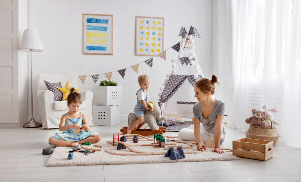 Moeder en kinderen spelend op een speelkleed in een lichte, sfeervolle kinderkamer