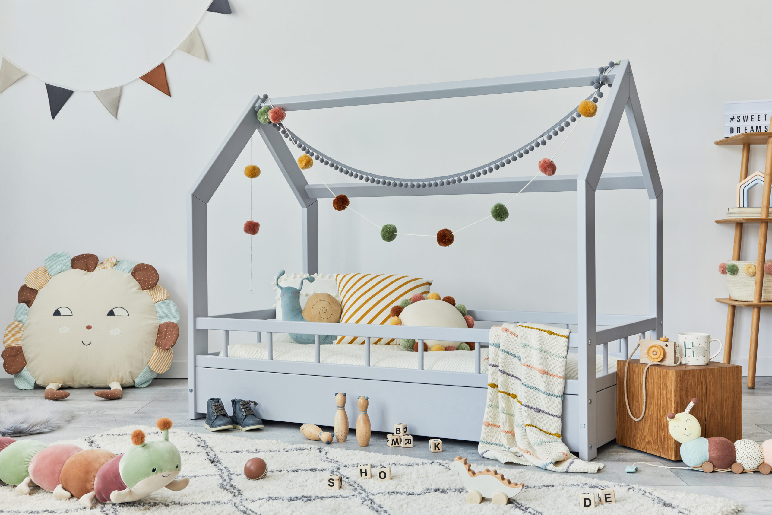 Kinderkamer met houten huisbed, zacht speelkleed en houten speelgoed in rustige kleuren