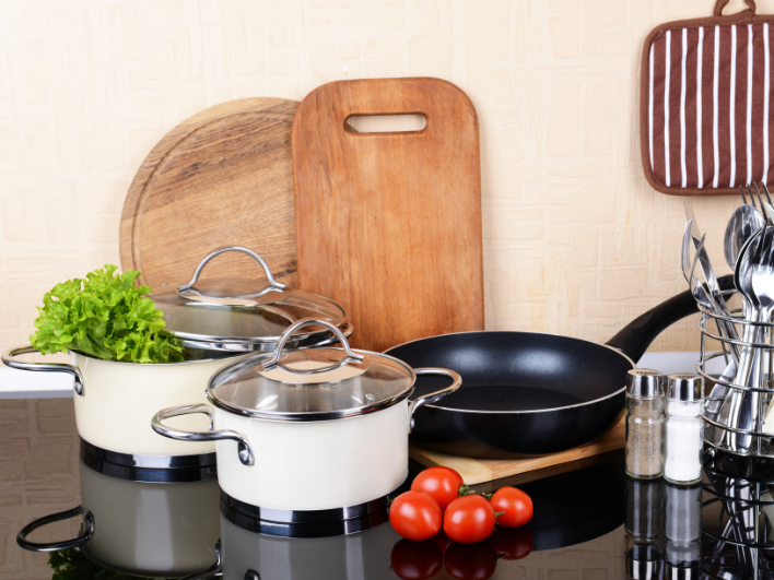 Verschillende pannen en keukengerei op een inductiekookplaat met verse groenten