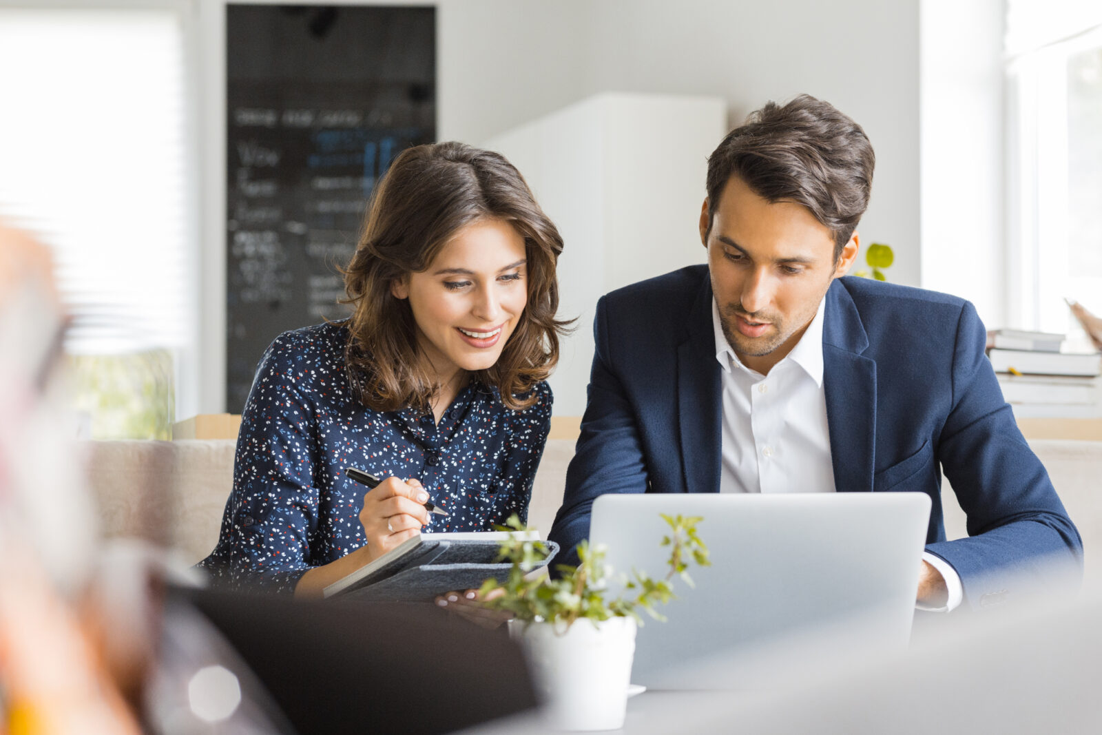 Jonge man en vrouw bespreken financiële keuzes aan tafel met laptop en notitieboekje